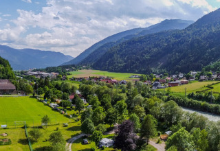 Luchtzicht op Drau Camping Sachsenburg glamping in Karinthië met groene weiden, rivier en bergen.