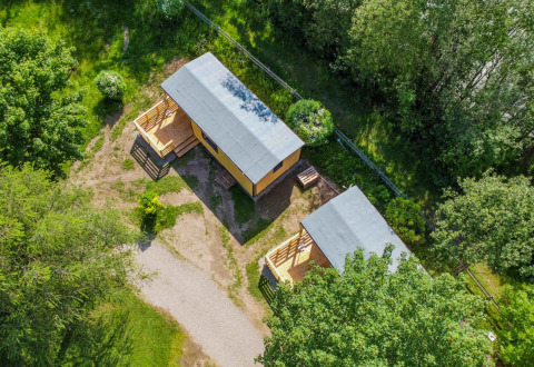 Vue aérienne de deux cabanes glamping entourées de verdure à Drau Camping Sachsenburg en Carinthie, Autriche.