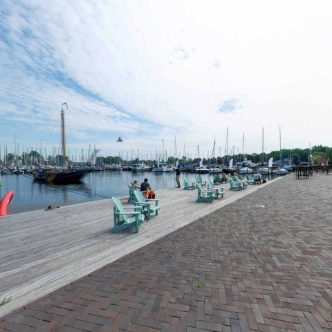 Barcos y personas en el muelle del parque vacacional Marina Parcs Naarden en Holanda Septentrional, Países Bajos.