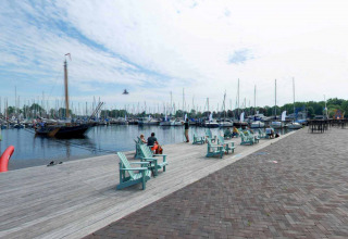 Boote und Menschen auf dem Steg im Marina Parcs Naarden Ferienpark in Nordholland, Niederlande an einem sonnigen Tag.