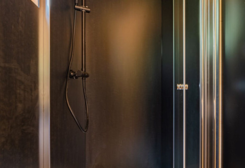 Moderne douche in een glampingaccommodatie bij Drau Camping Sachsenburg in Karinthië met zwarte wanden.