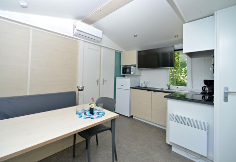 Moderne glampingbolig på Drau Camping Sachsenburg med køkken, spisebord og fladskærms-TV i Karintien.