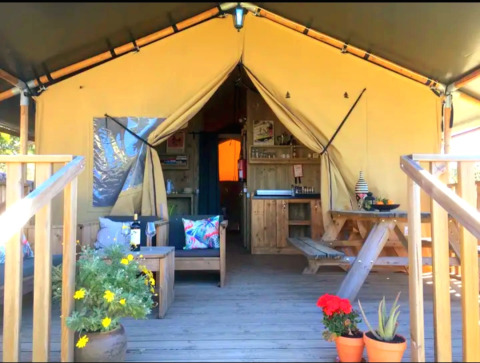 Quinta Vida Verde Glamping Portugal, hébergement sous tente avec terrasse en bois, table et plantes fleuries.