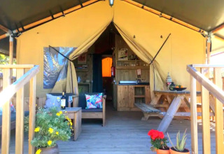 Quinta Vida Verde Glamping Portogallo, accogliente tenda su terrazza in legno con fiori e tavolo da picnic.