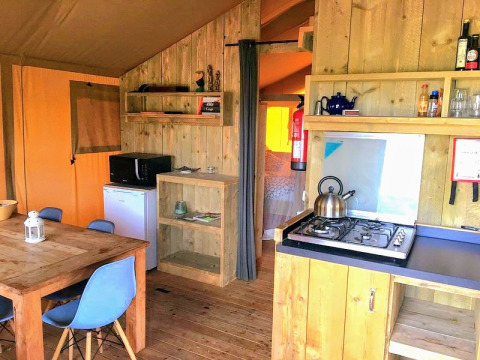Glamping accommodation at Quinta Vida Verde in Portugal with wooden furniture, dining area and kitchenette.