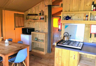 Alojamiento glamping en Quinta Vida Verde, Portugal, con muebles de madera, comedor y cocina pequeña.