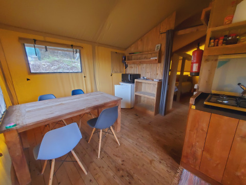 Indvendig udsigt over en hyggelig glamping-hytte på Quinta Vida Verde Glamping Portugal med spisebord og køkken.