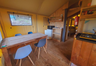 Vista interna di una confortevole tenda glamping a Quinta Vida Verde Glamping Portogallo con tavolo e cucina.