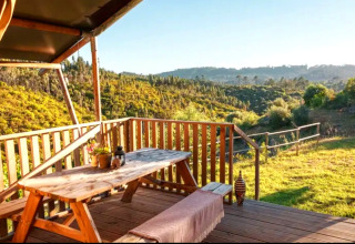 Træterrasse med udsigt over bakker og skove ved Quinta Vida Verde Glamping i Portugal, hyggelig udendørs spiseplads.