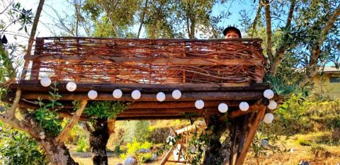 Rustikales Baumhaus bei Quinta Vida Verde - Glamping Portugal, geschmückt mit Lichterkette im Grünen.