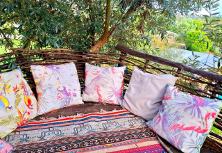 Glamping seating at Quinta Vida Verde in Portugal with colorful cushions and rustic wooden fencing outdoors.