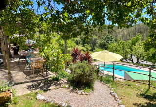 Udsigt over hyggelige udendørs siddeområder og pool ved Quinta Vida Verde Glamping Portugal under solskin.