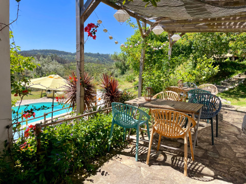 Terrasse ombragée de Quinta Vida Verde - Glamping Portugal avec vue sur la piscine et les collines verdoyantes.