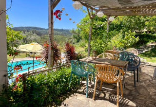 Terrasse ombragée de Quinta Vida Verde - Glamping Portugal avec vue sur la piscine et les collines verdoyantes.