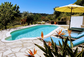 Piscina, tumbonas y sombrilla amarilla en Quinta Vida Verde - Glamping Portugal, rodeada de naturaleza.