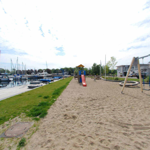 Speeltuin met glijbaan en schommel in het zand aan de jachthaven van Marina Parcs Naarden, Nederland.