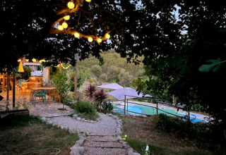 Sendero con luces, zona de estar y piscina en Quinta Vida Verde - Glamping Portugal al atardecer.