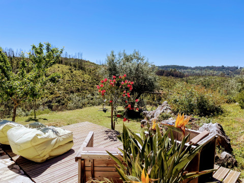 Uitzicht vanaf houten terras met zitzakken bij Quinta Vida Verde - Glamping Portugal, omgeven door groene heuvels.