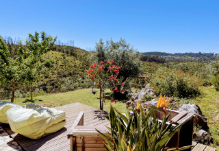 Vista desde una terraza de madera con sillones en Quinta Vida Verde - Glamping Portugal, rodeada de naturaleza.