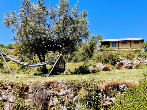 Hébergement glamping à Quinta Vida Verde au Portugal avec hamac, cabane dans l’arbre et ciel bleu.