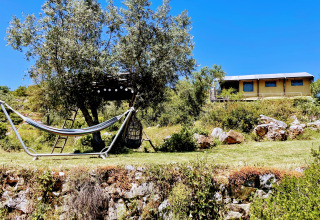 Glamping accommodation at Quinta Vida Verde in Portugal, featuring a hammock, treehouse, and clear sky.