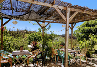 Udendørs siddeområde med træpergola og farverige stole i naturskønne omgivelser på Quinta Vida Verde.