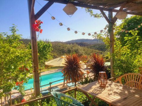 Udsigt fra en terrasse på Quinta Vida Verde Glamping Portugal med pool, grønne bakker og solskin.