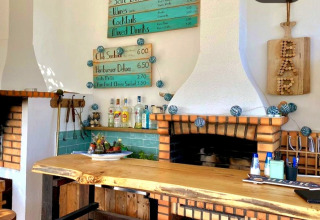 Acogedor bar en Quinta Vida Verde - Glamping Portugal con mostrador rústico, botellas y menús en la pared.