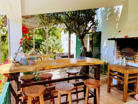 Buitenbar met houten krukken, barbecue en kleurrijke decoratie bij Quinta Vida Verde Glamping Portugal.