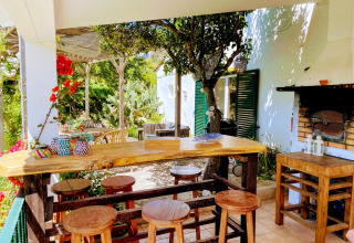Espace extérieur avec bar en bois, tabourets, barbecue et décor coloré à Quinta Vida Verde Glamping Portugal.