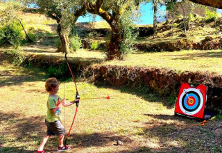 Un bambino pratica tiro con l'arco a Quinta Vida Verde - Glamping Portugal, immerso nella natura.
