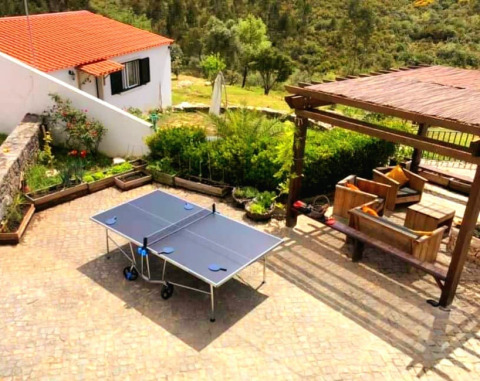 Outdoor area at Quinta Vida Verde Glamping Portugal featuring a ping pong table, seating, and garden views.