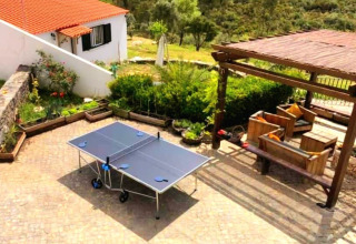 Zona exterior de Quinta Vida Verde Glamping Portugal con mesa de ping pong, asientos y pérgola rústica.