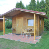 Wooden cabin with covered terrace, outdoor grill and chairs at Camping 'Am Leuchtturm' in Lower Saxony, Germany.