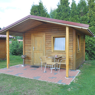 Cabane en bois avec terrasse couverte, barbecue et sièges au Camping 'Am Leuchtturm', Basse-Saxe, Allemagne.