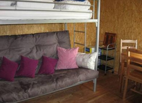 Interior of glamping accommodation at Camping 'Am Leuchtturm' with a bunk bed, sofa, table and chairs.