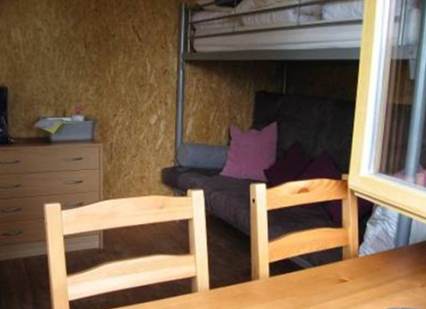 Interieur van een glamping blokhut met stapelbed, bank, houten tafel en stoelen op Camping 'Am Leuchtturm' in Nedersaksen.