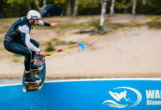 Wakeboarder con casco su cavo nel parco Wake & Ski Blauer See Garbsen, campeggio in Bassa Sassonia.