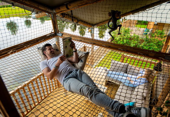Ein Mann entspannt und liest in einem Hängemattengitter bei Glamping De Rode Vos am See in Noord-Brabant.