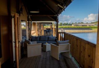 Terrazza in legno coperta con sedute vista lago a Glamping De Rode Vos - Glampingtenten Noord-Brabant.