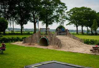 Spielplatz mit Sandhügel, Tunnel und viel Grün bei Glamping De Rode Vos in Noord-Brabant, Niederlande.