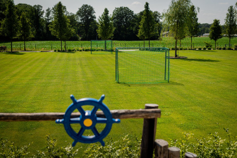 Campo da calcio verde con una porta a Glamping De Rode Vos - Glampingtenten Noord-Brabant, circondato dalla natura.