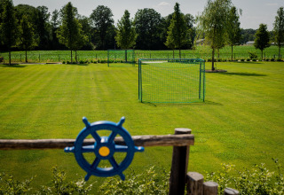 Groen voetbalveld met doel bij Glamping De Rode Vos - Glampingtenten Noord-Brabant, omgeven door bomen en groen.