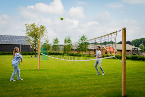 Twee personen spelen volleybal in het groen bij Glamping De Rode Vos, glampingtenten Noord-Brabant.