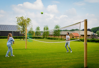 Deux personnes jouent au volley sur la pelouse du Glamping De Rode Vos, tentes glamping en Noord-Brabant.