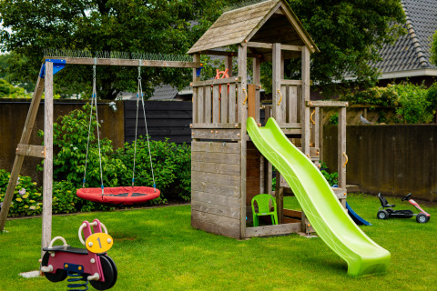 Speeltuin met schommel, glijbaan en houten speeltoestel bij Glamping De Rode Vos in Noord-Brabant.