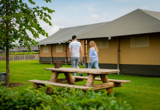 Couple at Glamping De Rode Vos, featuring glamping tents and wooden picnic table in Noord-Brabant.
