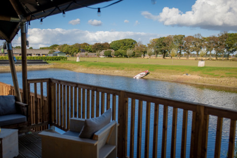 Vista desde una tienda glamping en Glamping De Rode Vos en Noord-Brabant con lago y bote en la orilla.