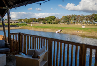 Vista desde una tienda glamping en Glamping De Rode Vos en Noord-Brabant con lago y bote en la orilla.