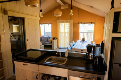 Innenansicht eines luxuriösen Glamping-Zeltes mit moderner Küche und Essbereich in Noord-Brabant.